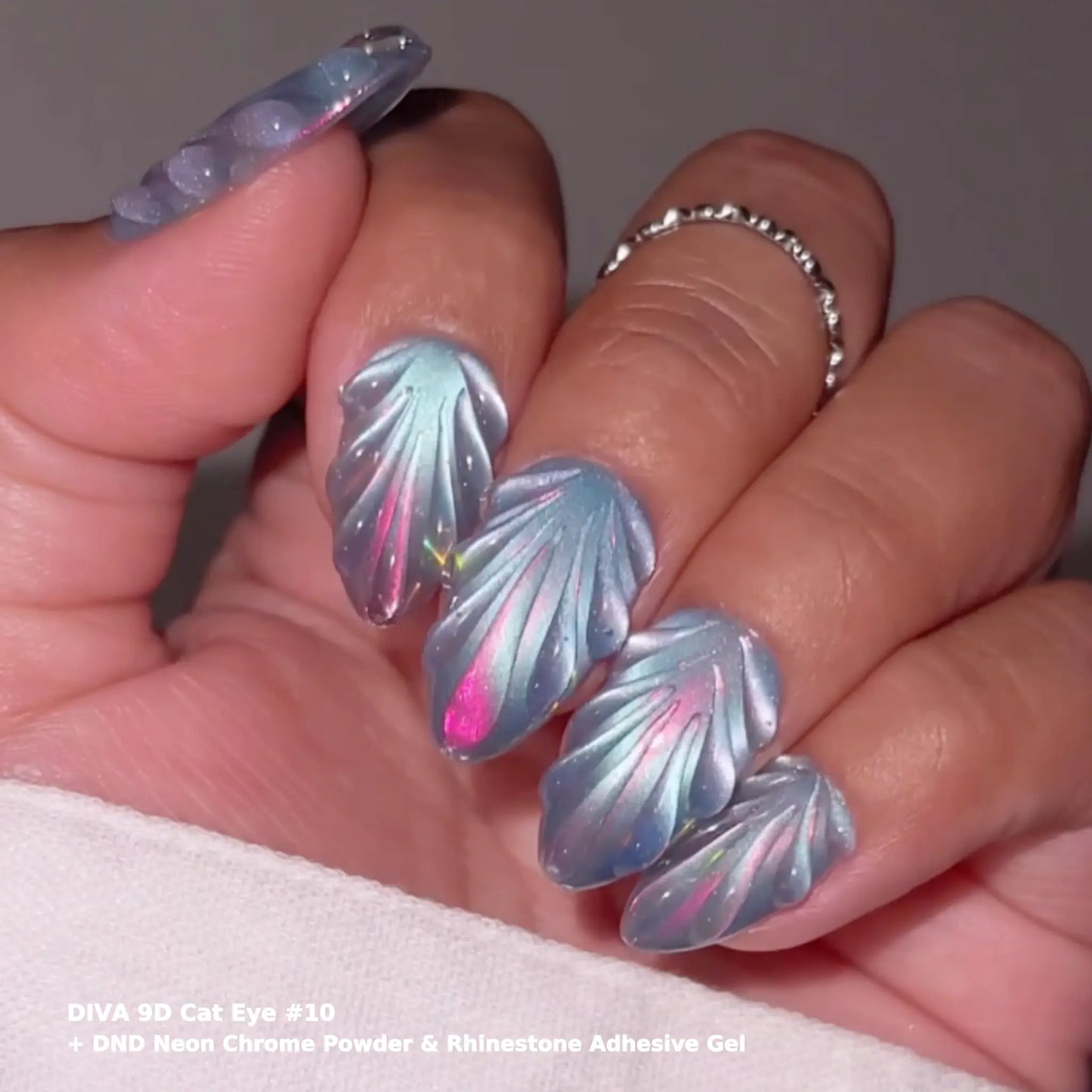 Hand with sculpted leaf-shaped iridescent nail art, DIVA 9D Cat Eye #10 with DND Neon Chrome Powder and Rhinestone Adhesive Gel