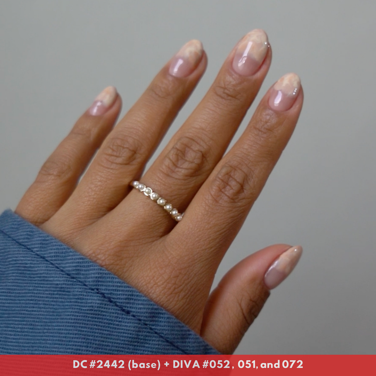 Hand with frosted chai-latte colored nails featuring a hand-painted nail art design