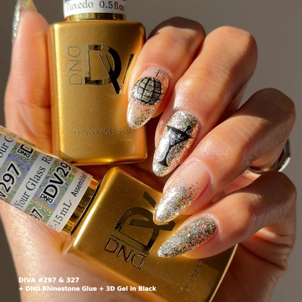 Hand with glittery silver nails and black 3D gel line art holding gold DND bottles, DIVA #297 and #327 with DND Rhinestone Glue and 3D Gel in black