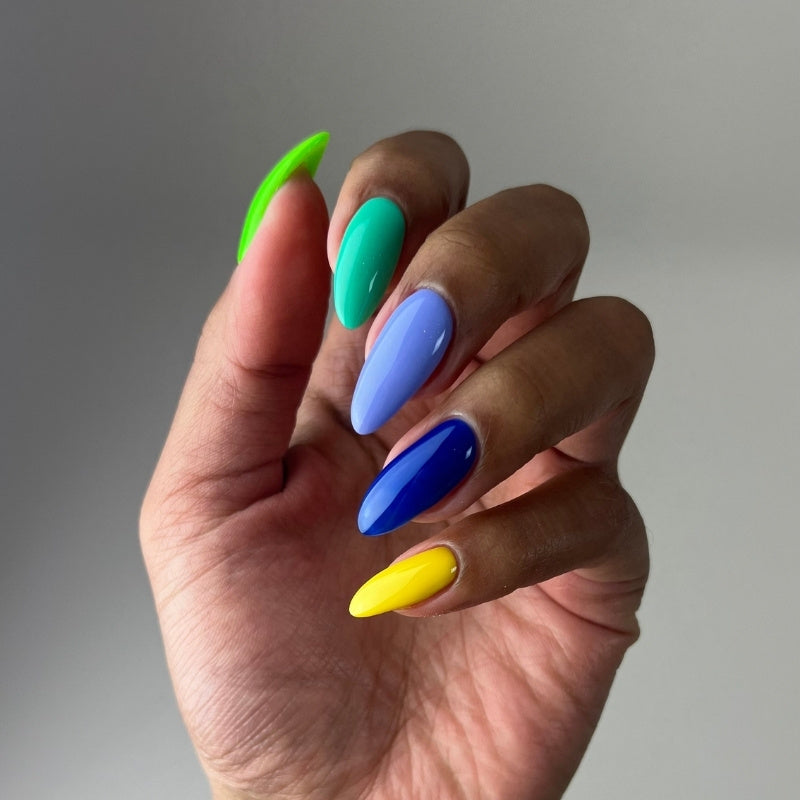 Hand with five nails in green, teal, blue, cornflower blue, and yellow, showcasing DND DIVA shades 190, 193, 196, 199, and 203