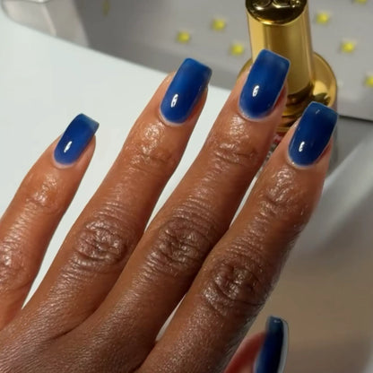 Close-up of hand with glossy navy blue manicured nails in DC #021 gel nail polish