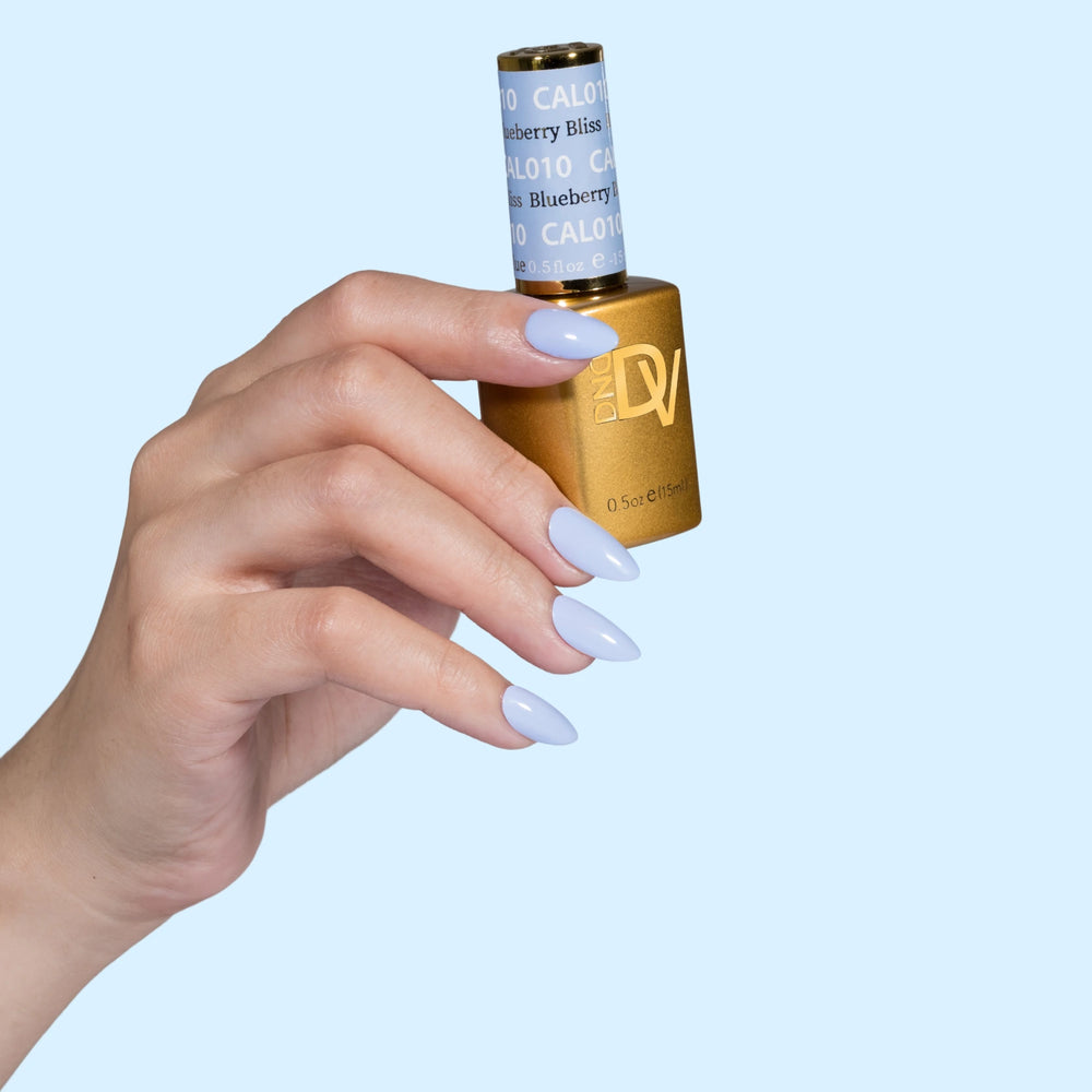 Hand holding gold-capped bottle labeled Blueberry Bliss, blue background