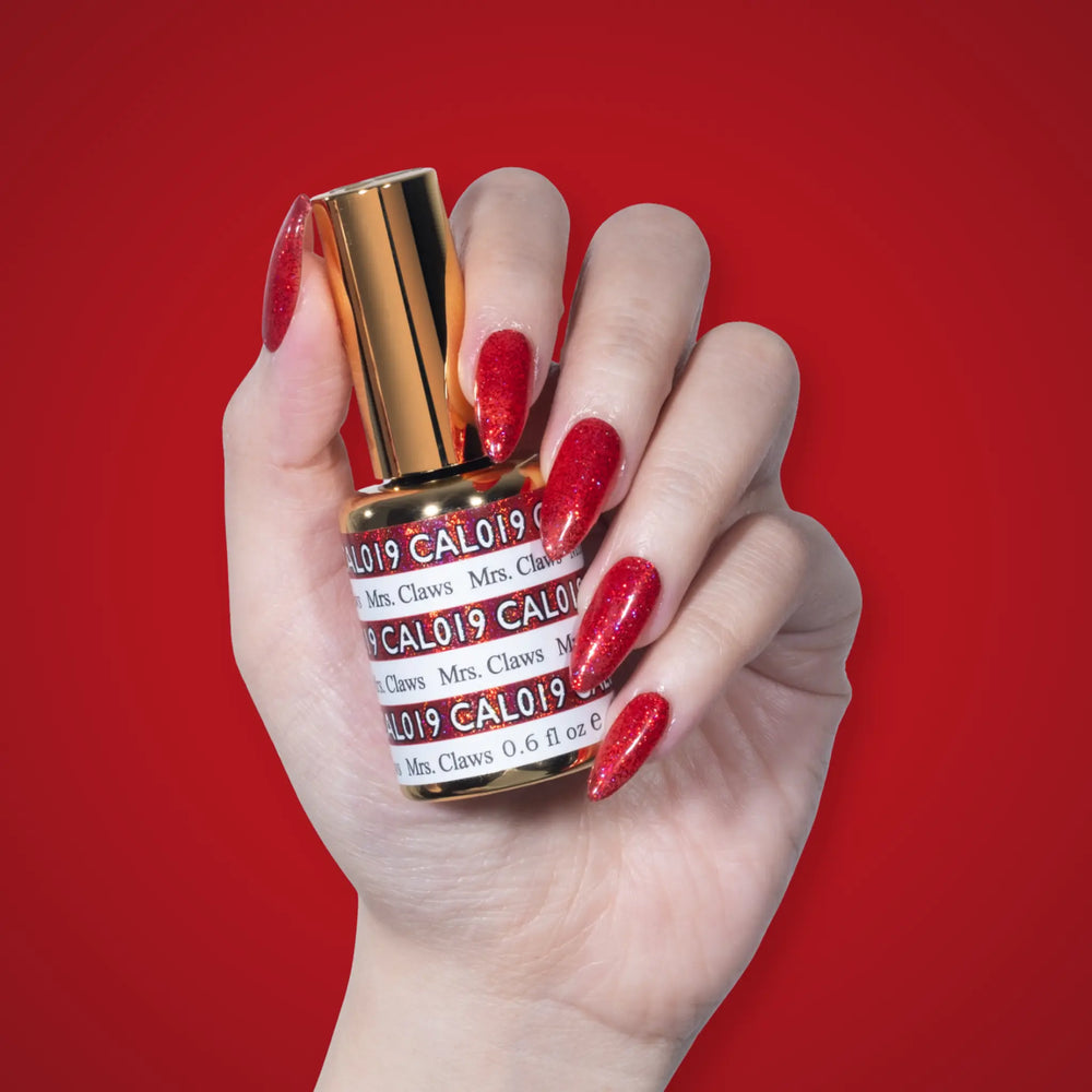 Hand with glossy glittery red nails holding a gold-capped DND CAL019 Mrs. Claws bottle on a red background