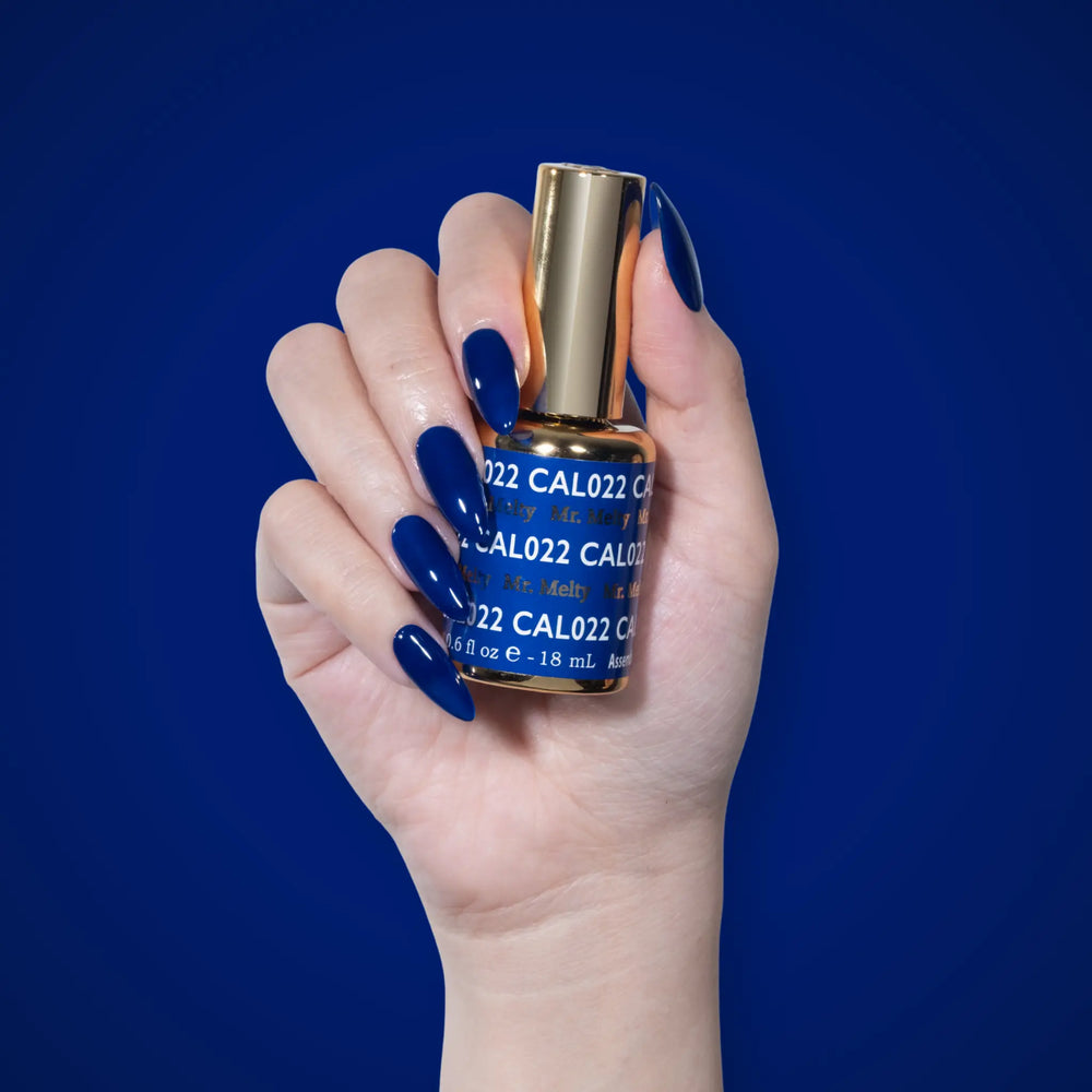 Hand with dark blue nails holding a DND CAL022 Mr. Melty bottle against a blue background