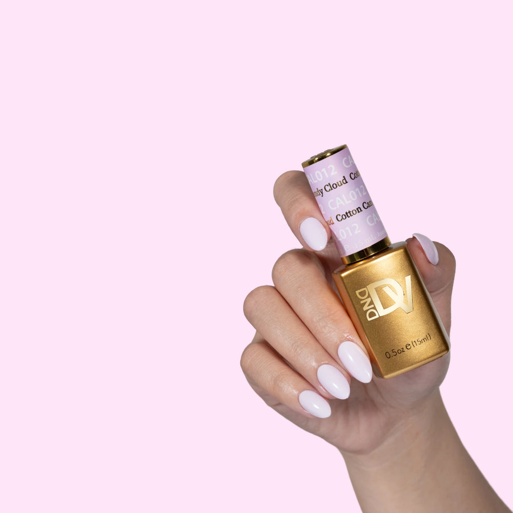 Hand holding gold-capped bottle labeled Cotton Candy Cloud, pink background