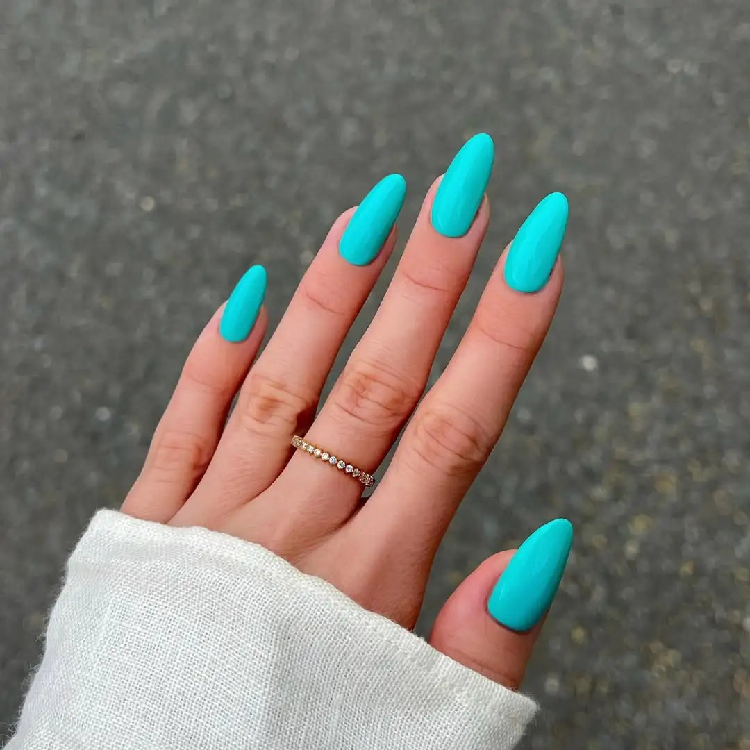 Hand with long oval nails and turquoise aqua tiffany blue nail polish on a gray pavement background
