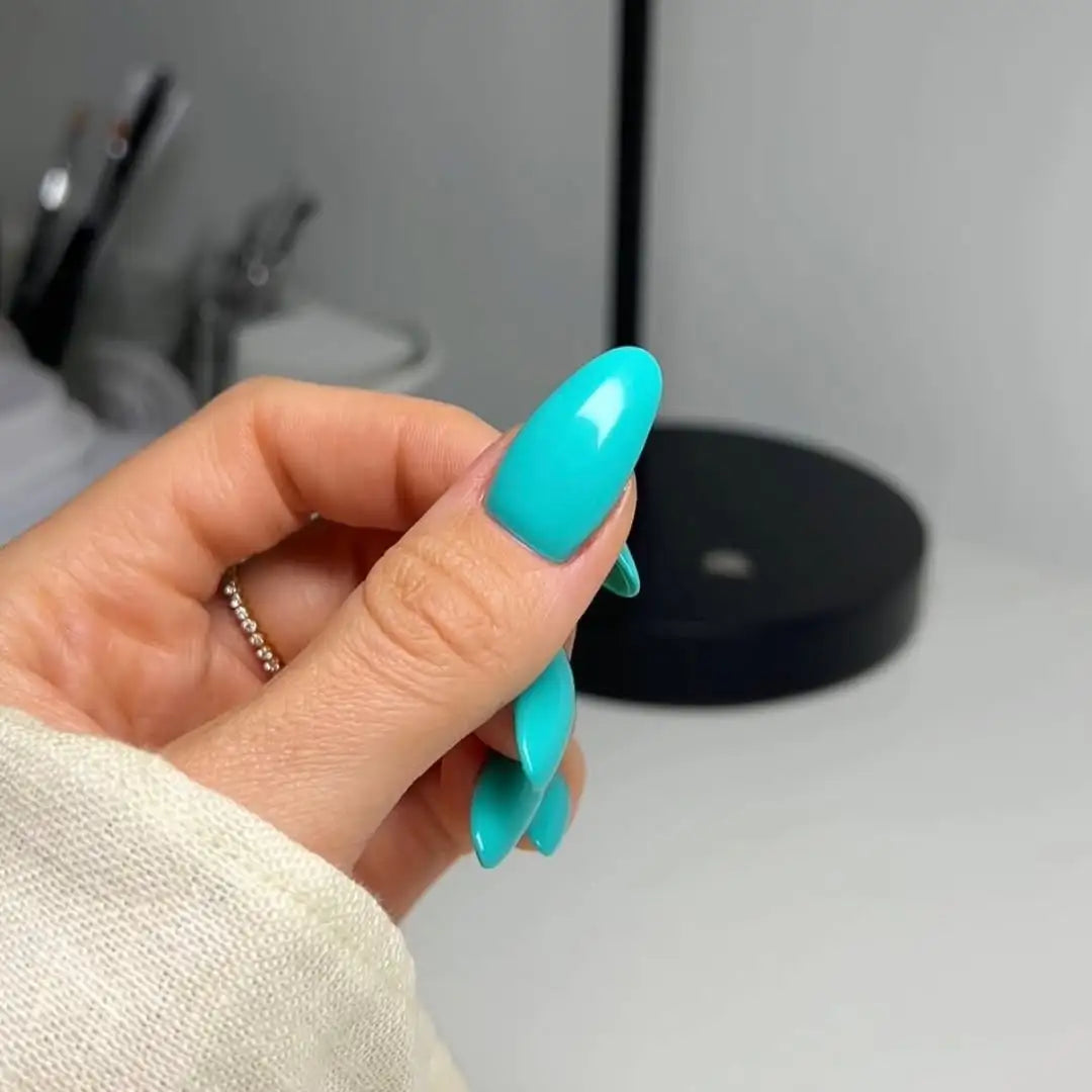Hand with long oval almond nails and turquoise aqua tiffany blue nail polish with a blurred background