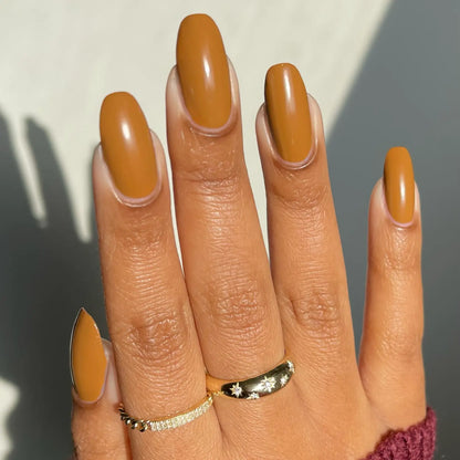 Close-up of hand with long almond nails painted in DC Cookie Chips #317 gel nail polish, glossy warm caramel brown