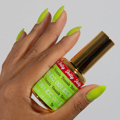 Hand with long almond-shaped nails wearing DC Jelly Tennis fluorescent green-yellow jelly nail polish, holding a bottle of DND nail polish