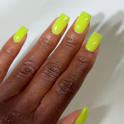 Close-up of a hand with long square-shaped nails wearing DC Jelly Tennis fluorescent green-yellow jelly nail polish