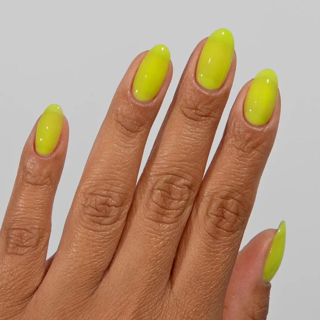 Hand with long almond nails wearing glossy DC Jelly Yellow jelly gel nail polish