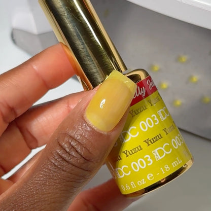 Close-up of a yellow jelly manicured nail holding a bottle of DC Jelly Yuzu gel nail polish