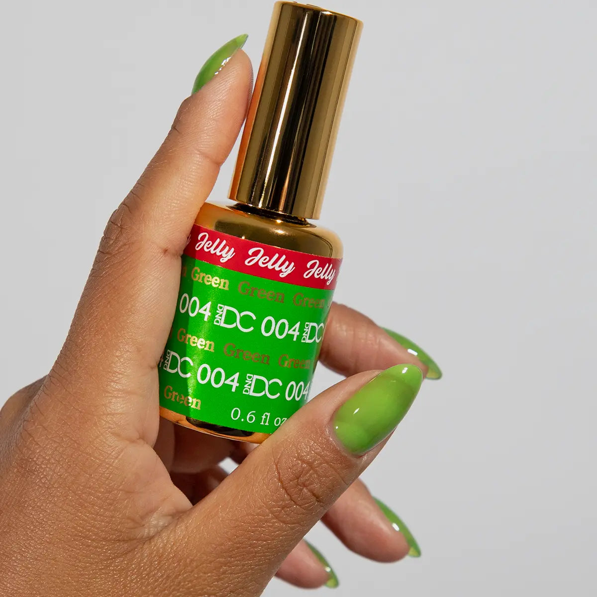 Hand with green jelly manicure holding a bottle of DC Jelly Green gel nail polish
