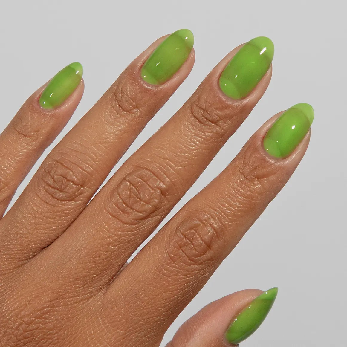 Hand with long almond nails wearing glossy DC Jelly Green jelly gel nail polish