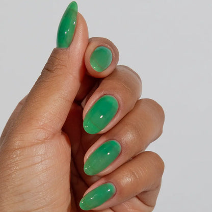Close-up of a hand with long almond-shaped nails wearing DC Jelly Kelly emerald green jelly nail polish