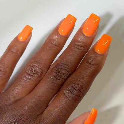 Close-up of a hand with long square-shaped nails wearing DC Jelly Orange true orange jelly nail polish