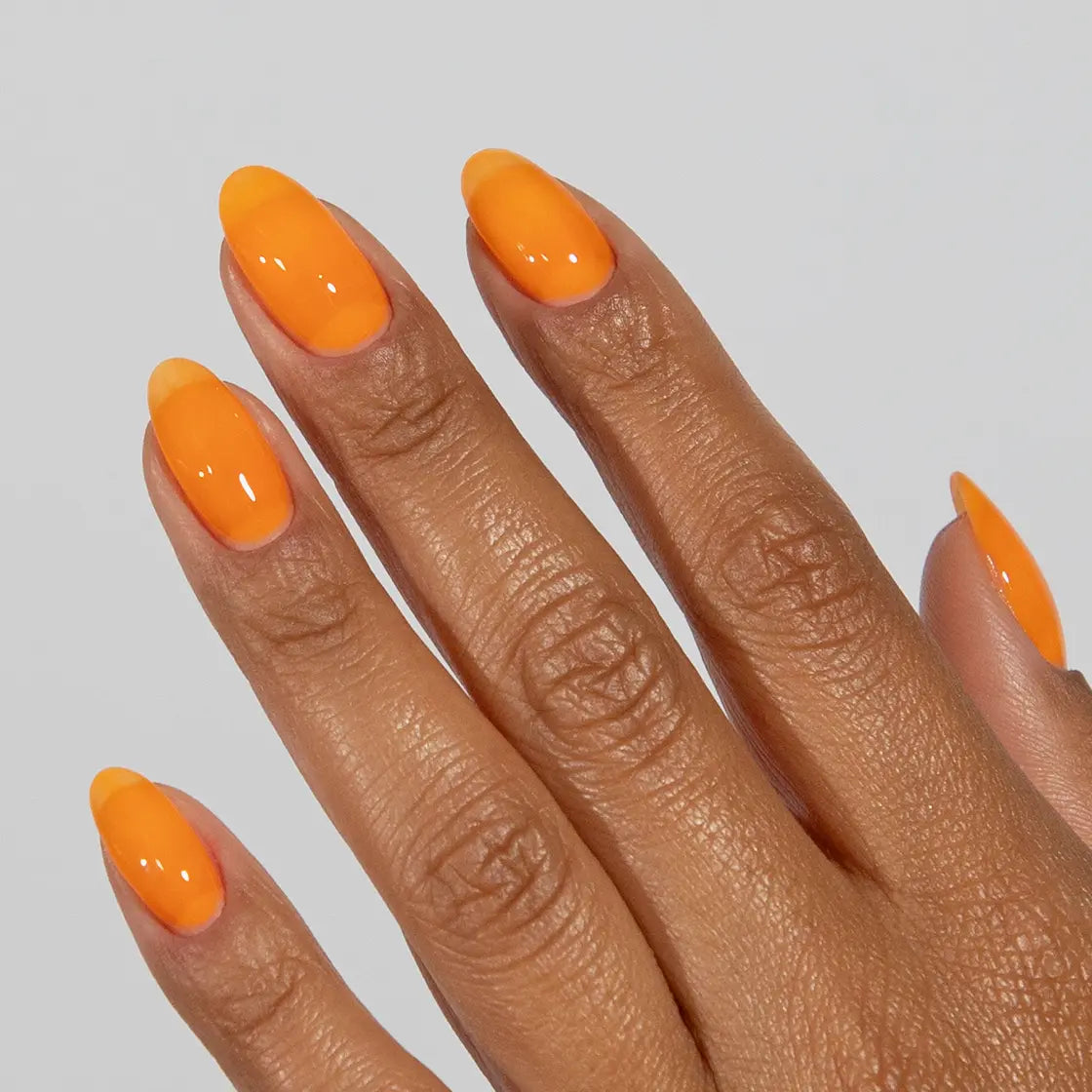 Close-up of a hand with long almond-shaped nails wearing DC Jelly Orange true orange jelly nail polish