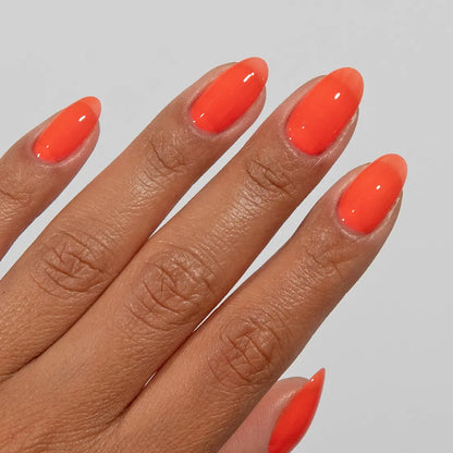 Close-up of a hand with long almond-shaped nails wearing DC Jelly Citrus fiery orange jelly nail polish