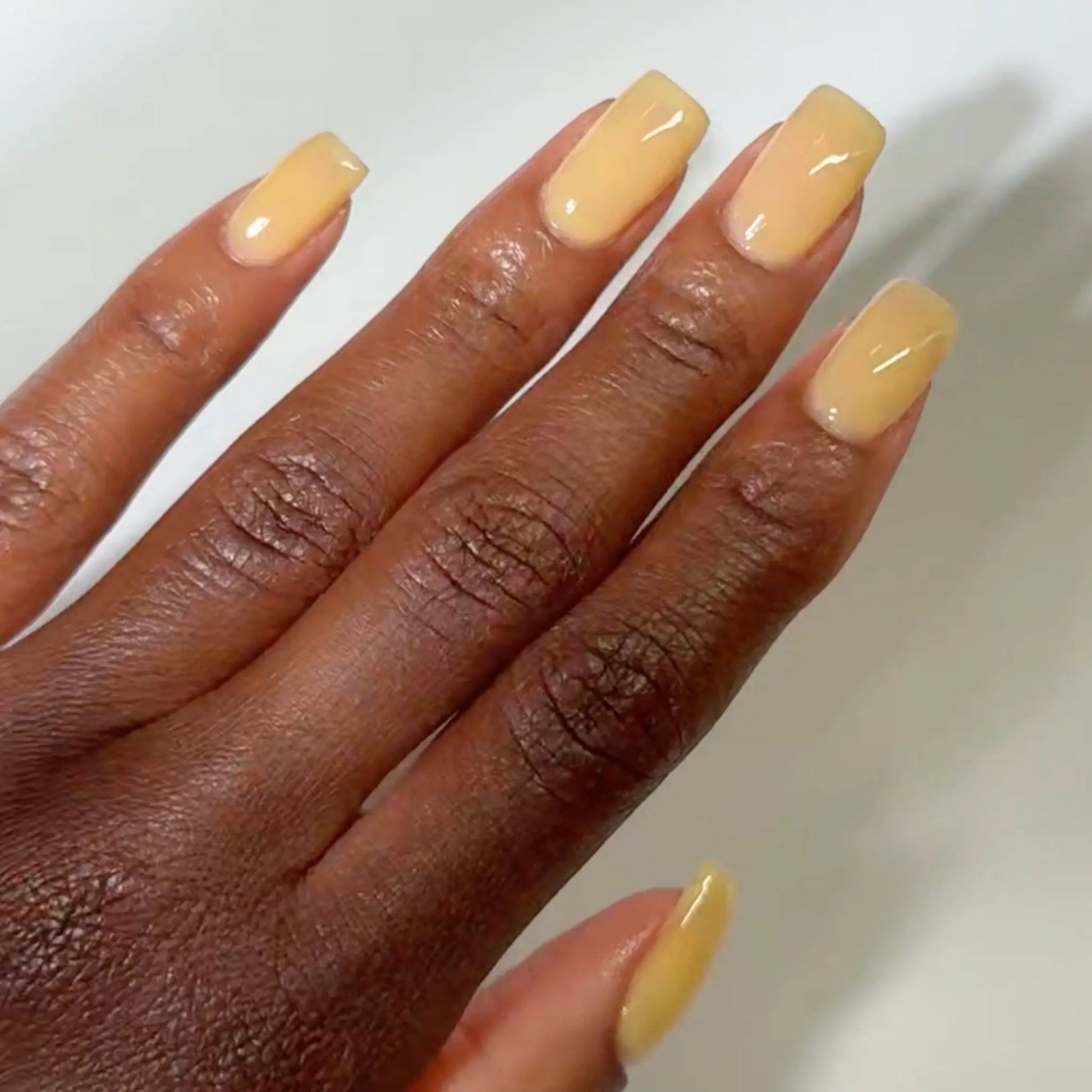 Close-up of a hand with long square-shaped nails wearing DC Jelly Merengue Pie pale yellow jelly nail polish