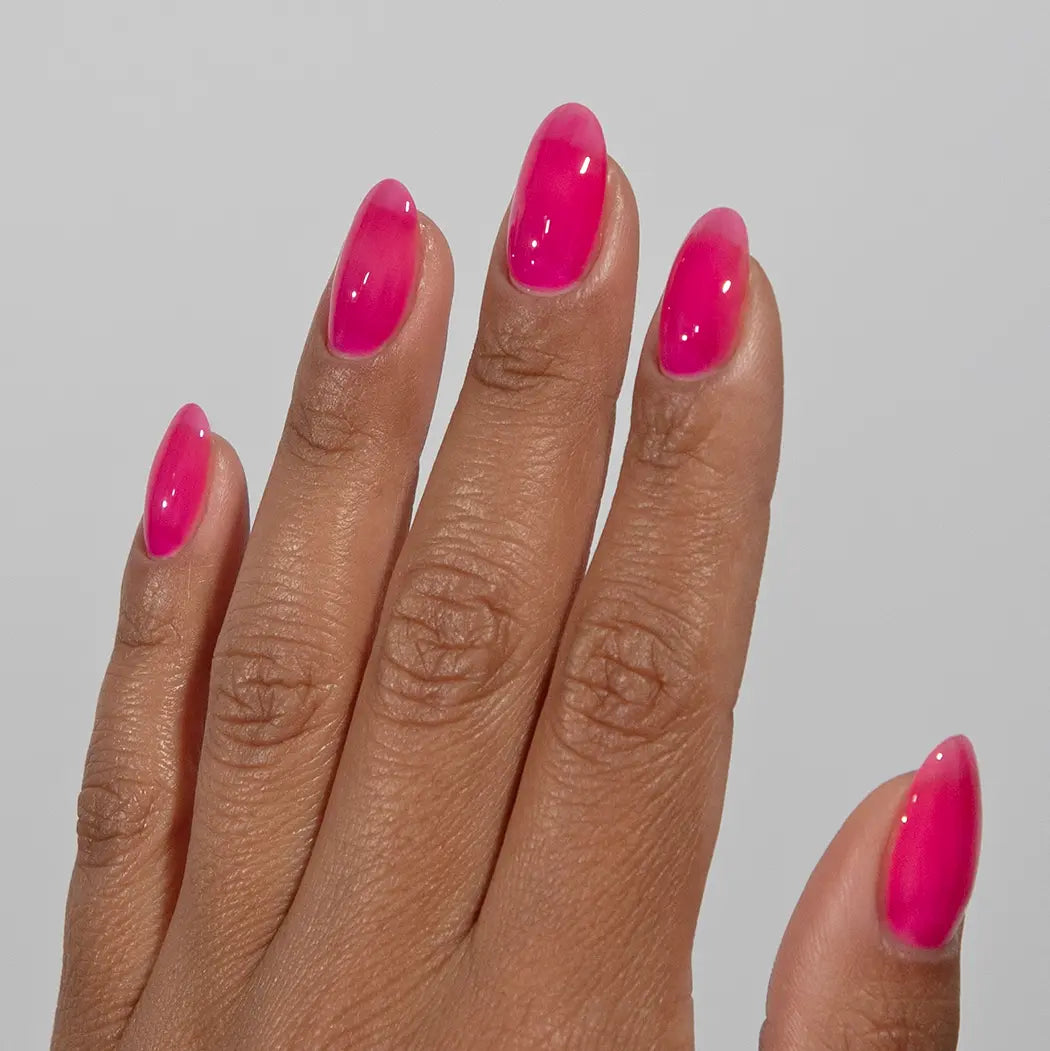 Close-up of fingers with glossy DC Jelly Hot Pink jelly gel nail polish manicure