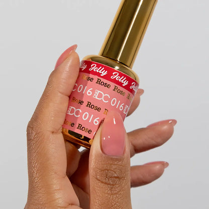 Hand with long almond nails wearing DC Jelly Rose dusty pink jelly nail polish, holding a bottle of DND nail polish