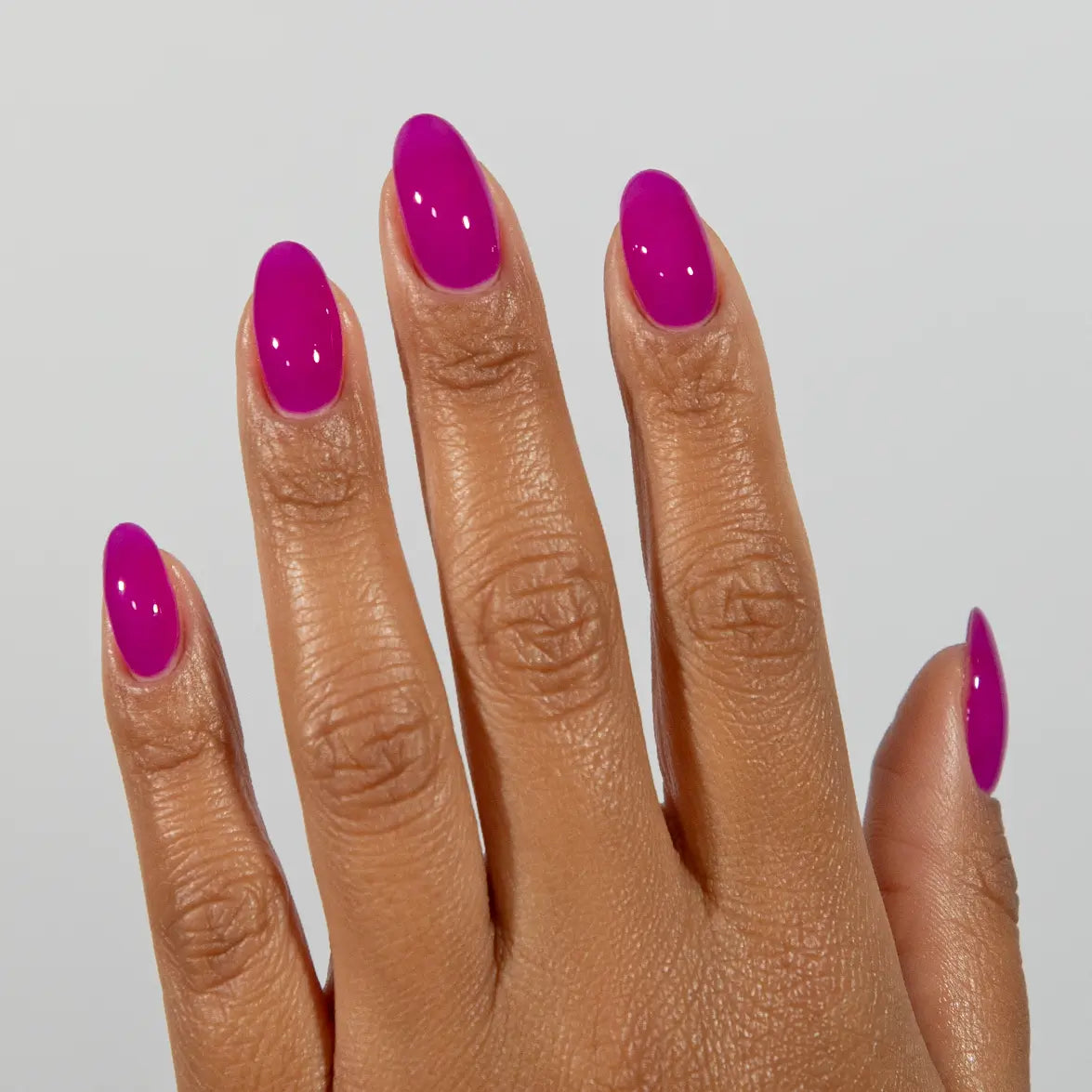 Hand with long almond nails wearing DC Jelly Amethyst vivid magenta-purple jelly nail polish
