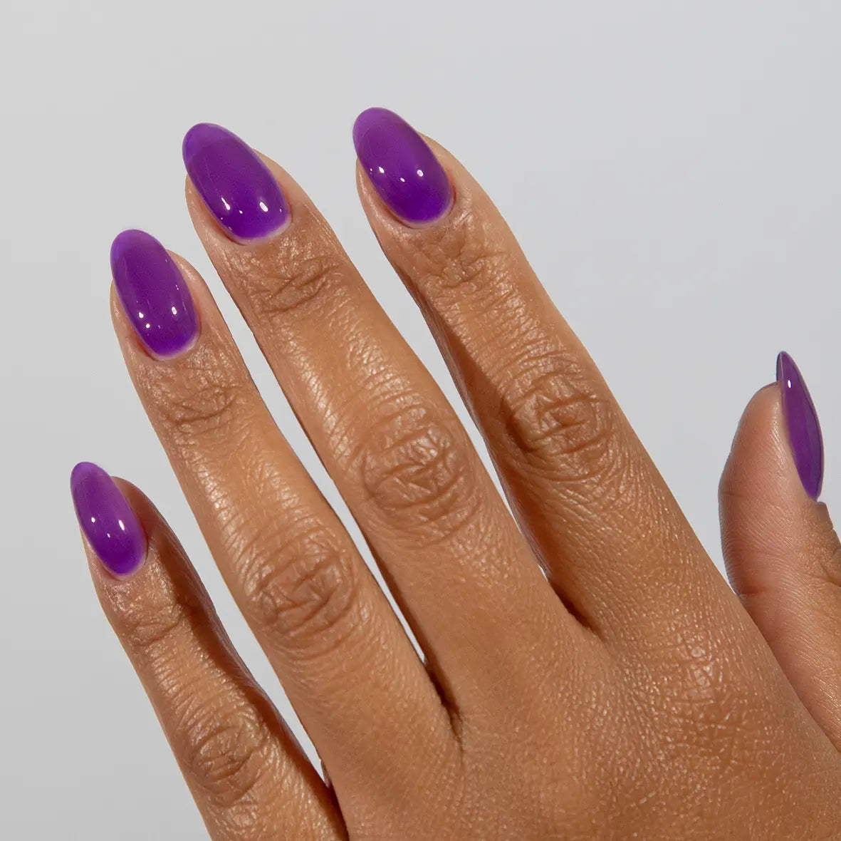 Hand with long almond nails wearing glossy DC Jelly Iris purple jelly gel nail polish