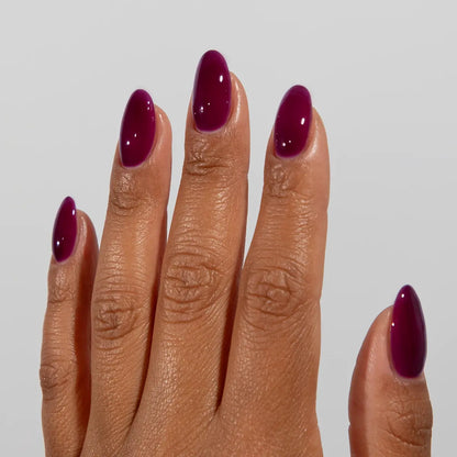 Hand with long almond nails wearing DC Jelly Grape deep burgundy-purple jelly nail polish
