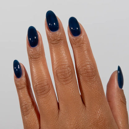 Hand with long almond nails wearing DC Jelly Sapphire deep sea blue jelly nail polish