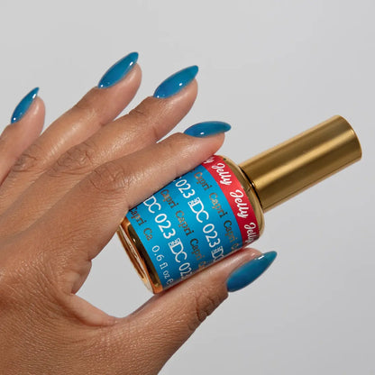 Hand with long almond nails wearing DC Jelly Capri bright azure blue jelly nail polish, holding a bottle of DND nail polish