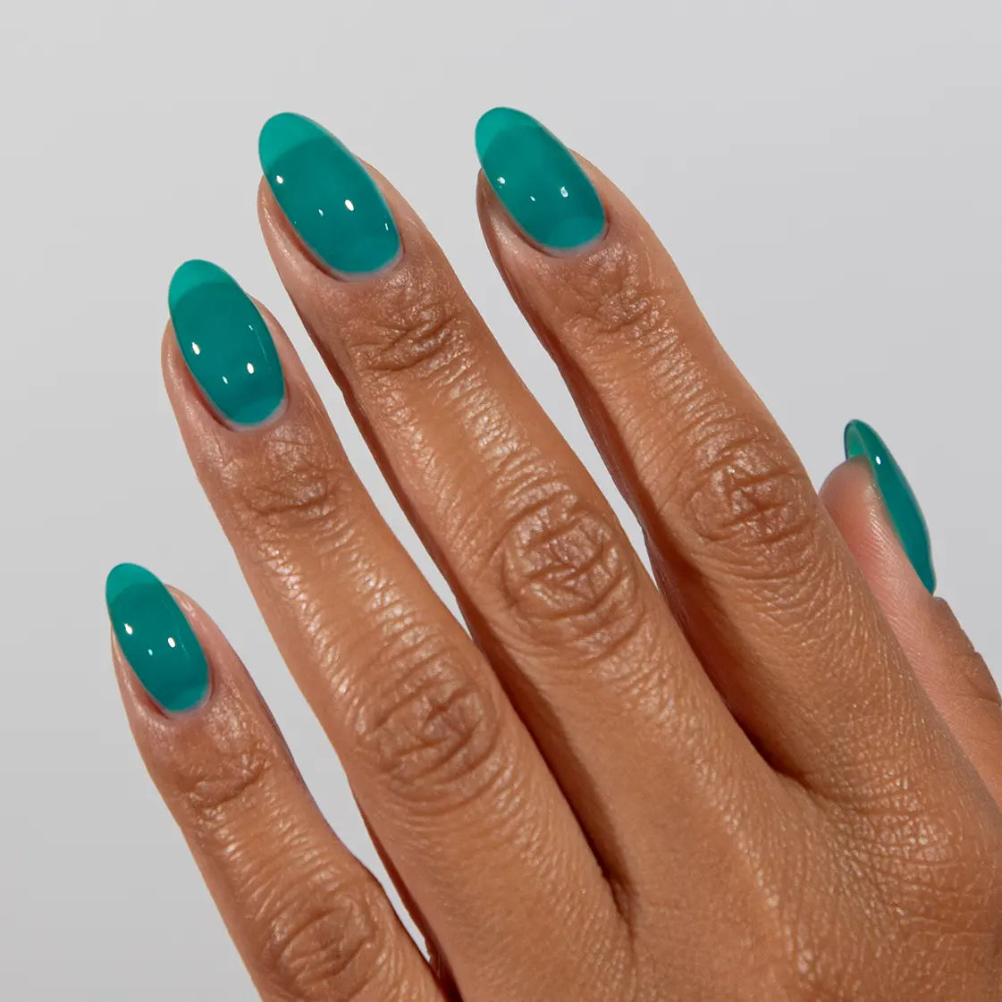 Hand with long almond nails wearing DC Jelly Jade turquoise green-blue jelly nail polish