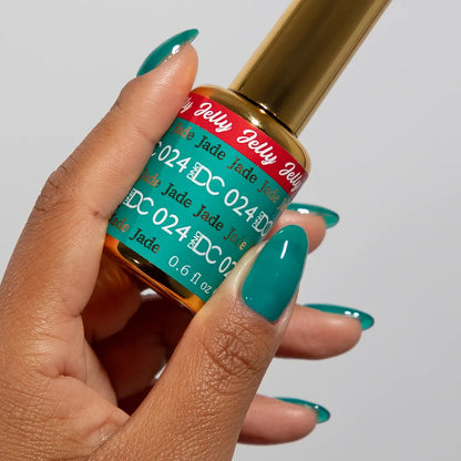 Hand with long almond nails wearing DC Jelly Jade turquoise green-blue jelly nail polish, holding a bottle of DND nail polish