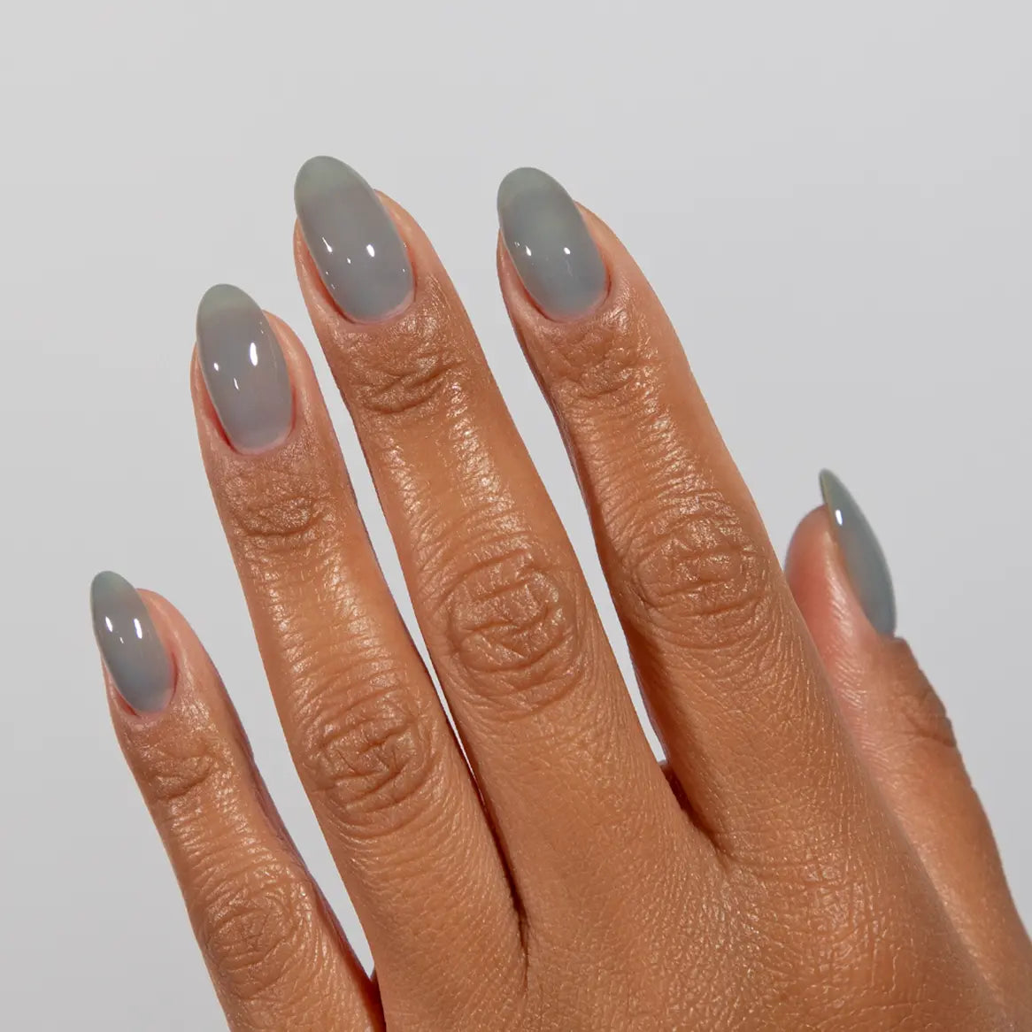 Hand with long almond nails wearing DC Jelly Storm warm grey jelly nail polish