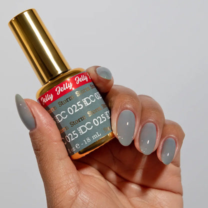 Hand with medium round nails wearing DC Jelly Storm warm grey jelly nail polish, holding a bottle of DND nail polish