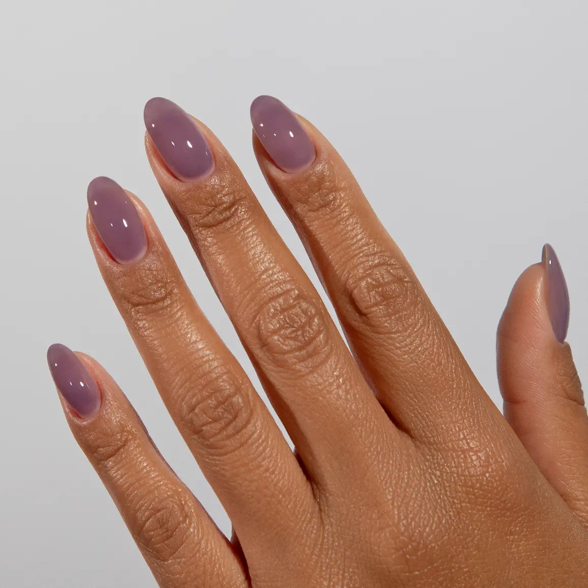 Hand with long almond nails wearing DC Jelly Plum Haze muted purple jelly nail polish