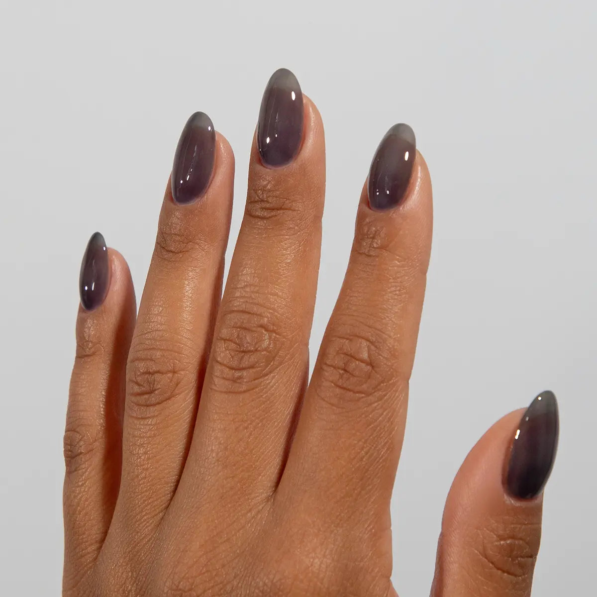 Hand with long almond nails wearing DC Jelly Coal dark smoky grey jelly nail polish
