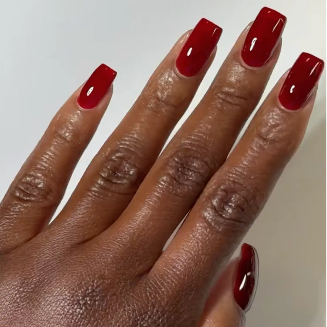 Hand with medium square nails wearing DC Jelly Sangria deep red jelly nail polish