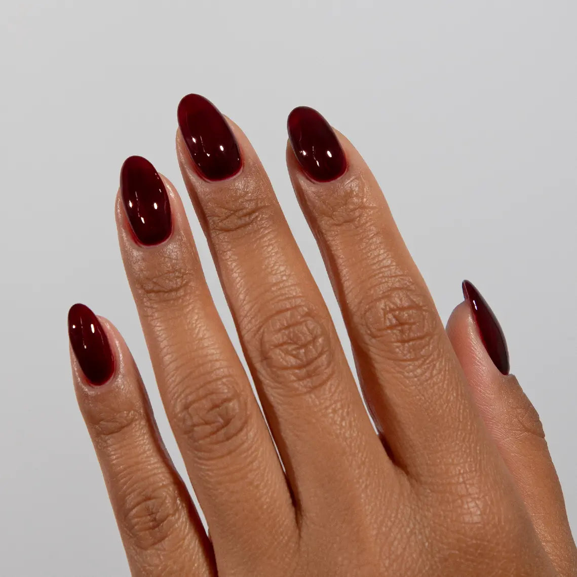 Hand with long almond nails wearing DC Jelly Cabernet scarlet red jelly nail polish