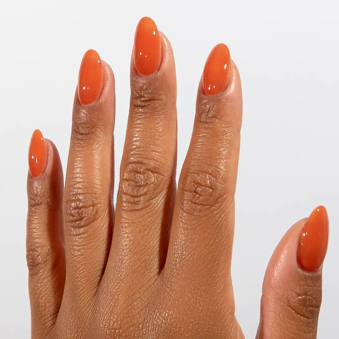 Close-up of a hand with long almond-shaped nails wearing DC Jelly Terracotta brown-orange jelly nail polish
