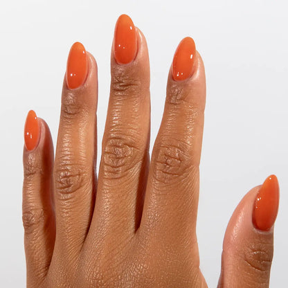 Close-up of a hand with long almond-shaped nails wearing DC Jelly Terracotta brown-orange jelly nail polish