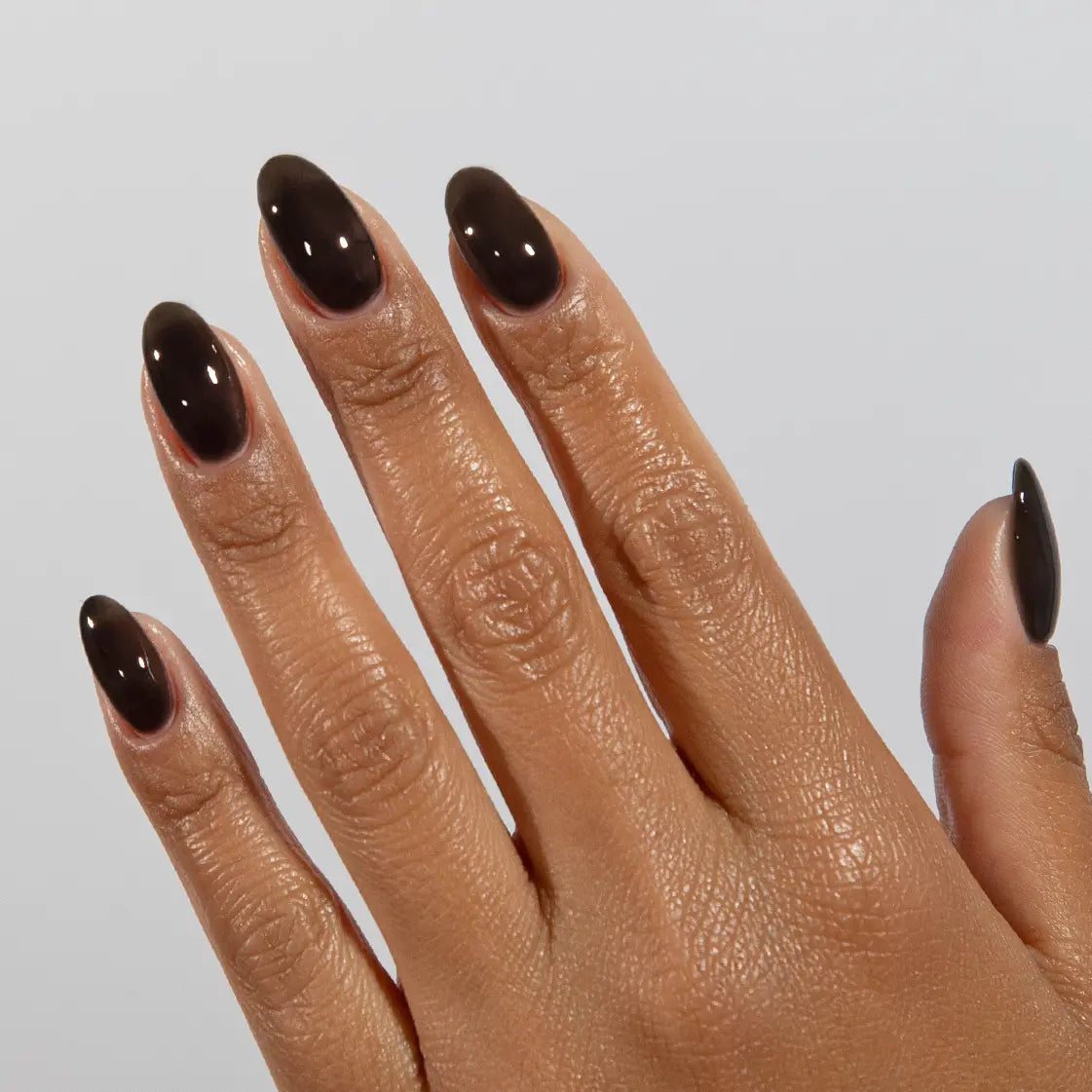 Close-up of a hand with long almond-shaped nails wearing DC Jelly Inky Black jelly nail polish
