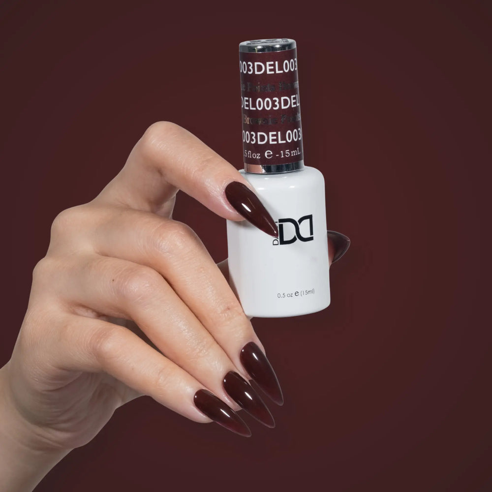 Hand with glossy dark brown nails holding a DND DEL #003 Brownie Points gel polish bottle