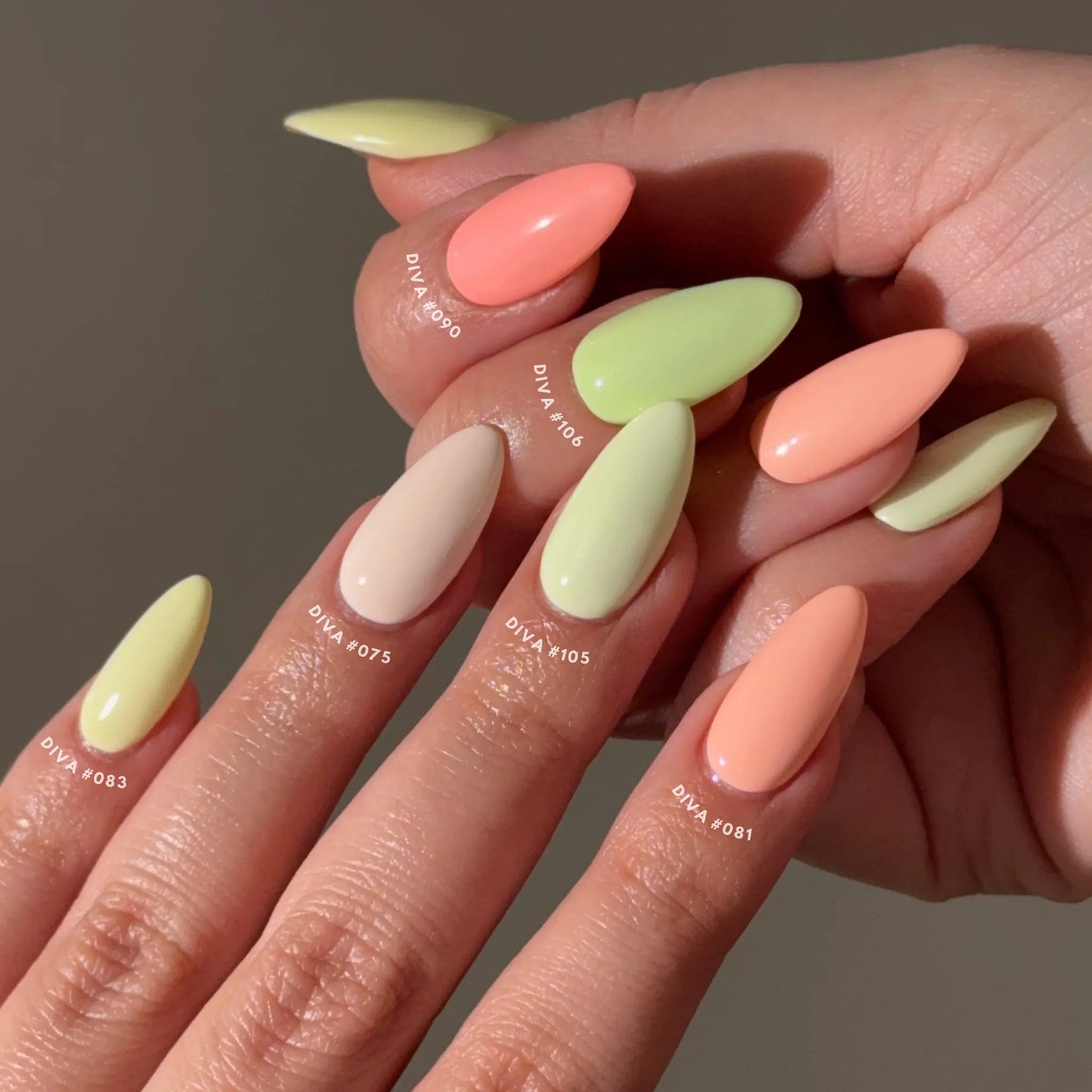 Close-up of hands with citrus pastel-colored nails on a neutral background
