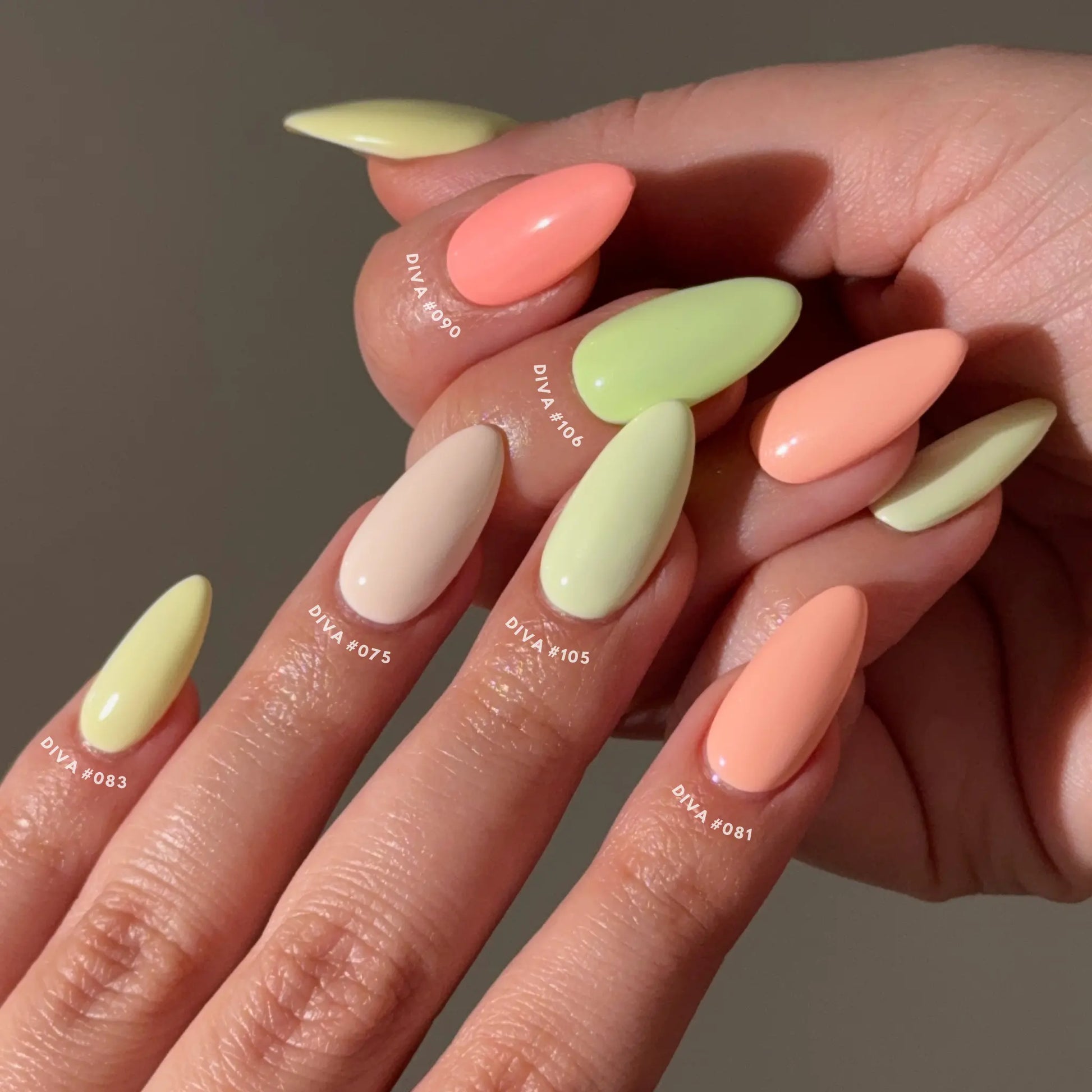 Close-up of hands with citrus pastel-colored nails on a neutral background
