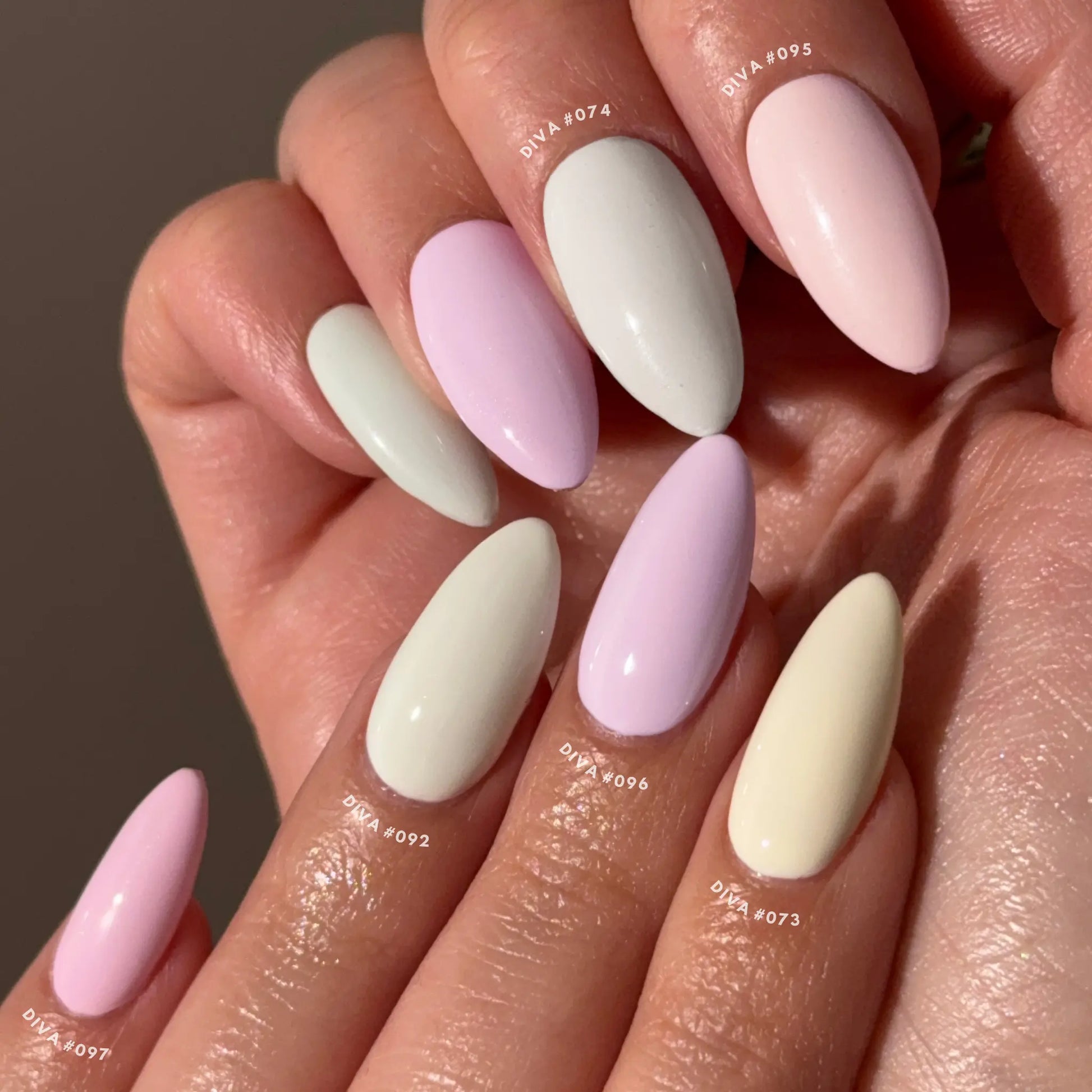 Close-up of hands with pastel pink, cream, and white nail colors on a neutral background