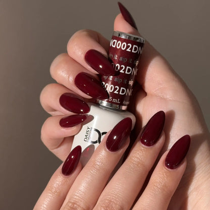 Hand with warm red nail polish holding a bottle of DND nail polish.