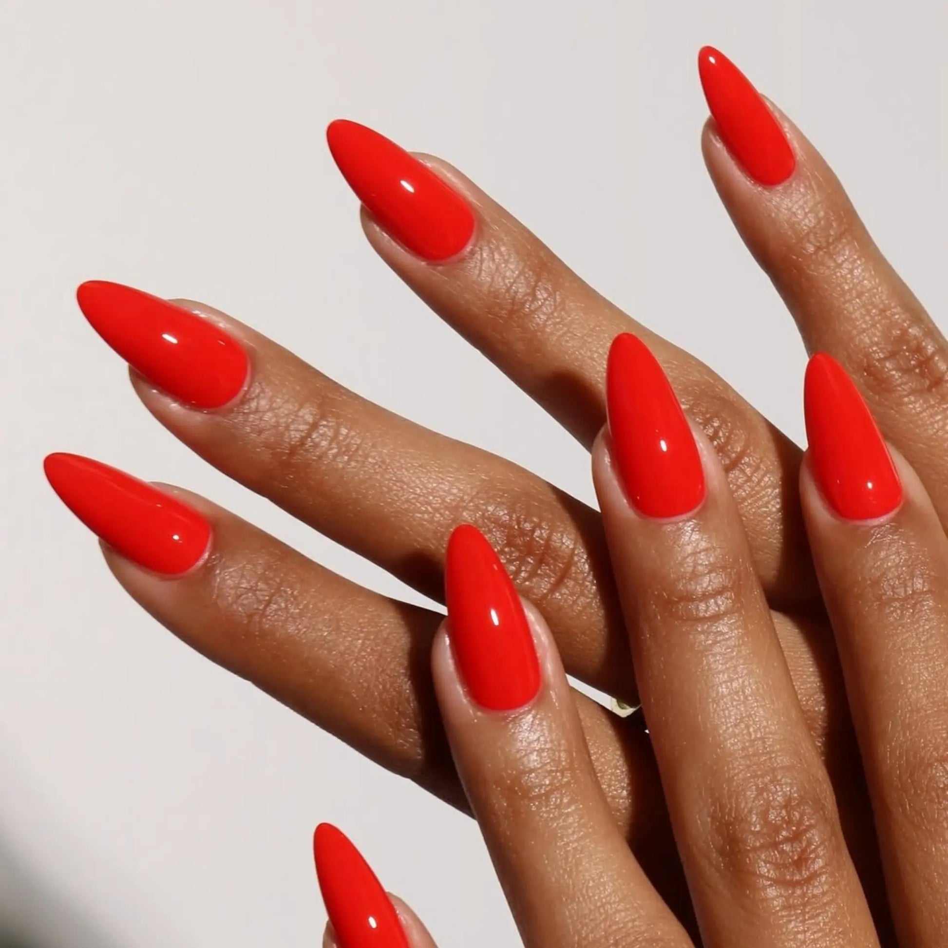 Close-up of hand with red stiletto nails wearing DND Scorching nail polish #006