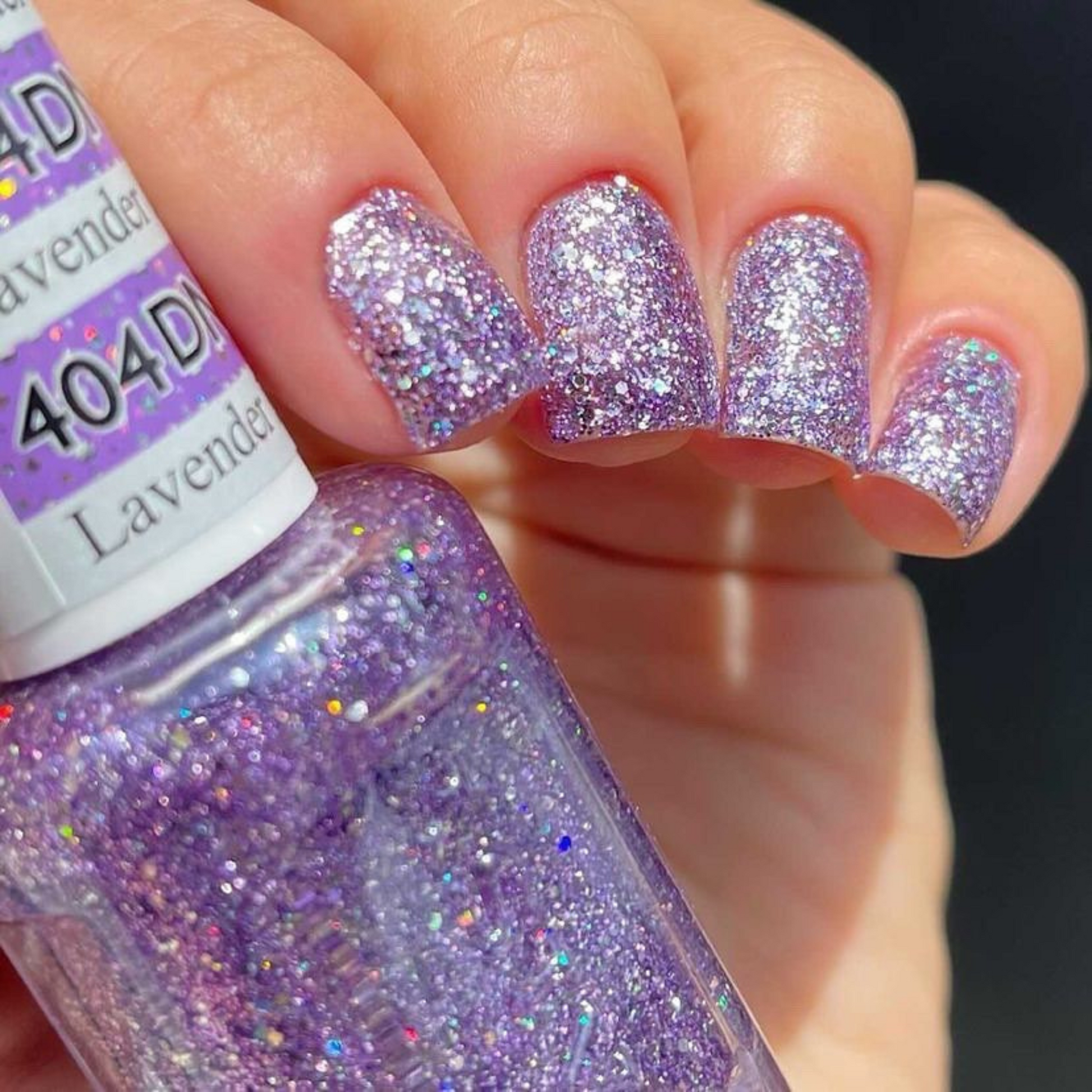 Hand with short square nails wearing Lavender Daisy Star purple glitter nail polish with silver flecks