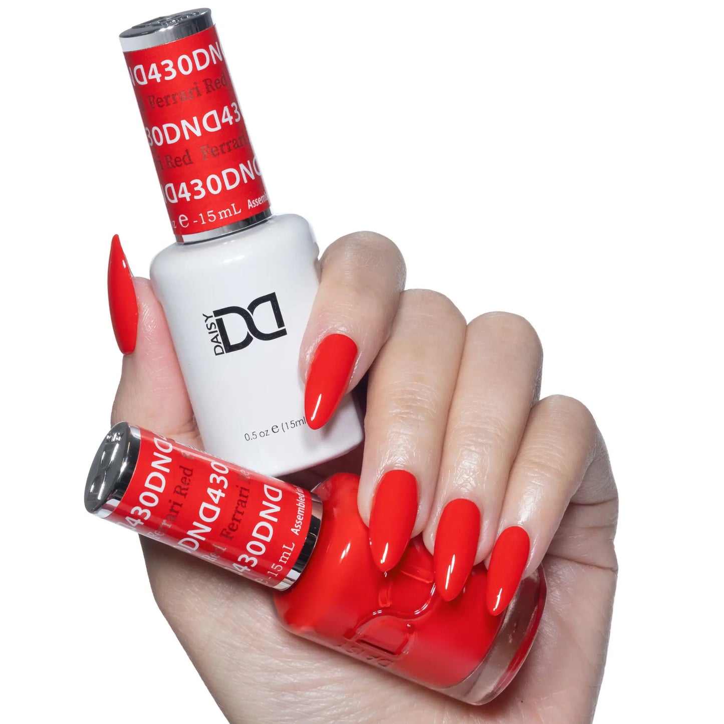 Hand holding a duo set of DND polish bottles with classic bright red almond nails.