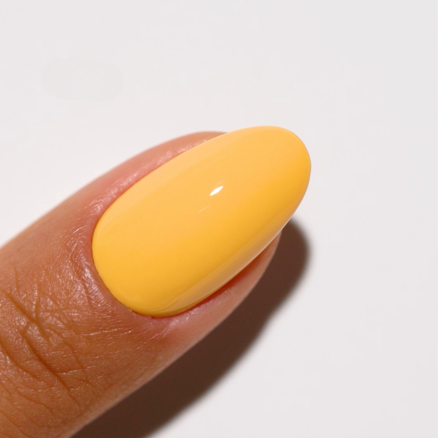 Warm honey tone nail polish in golden yellow shade on rounded nails